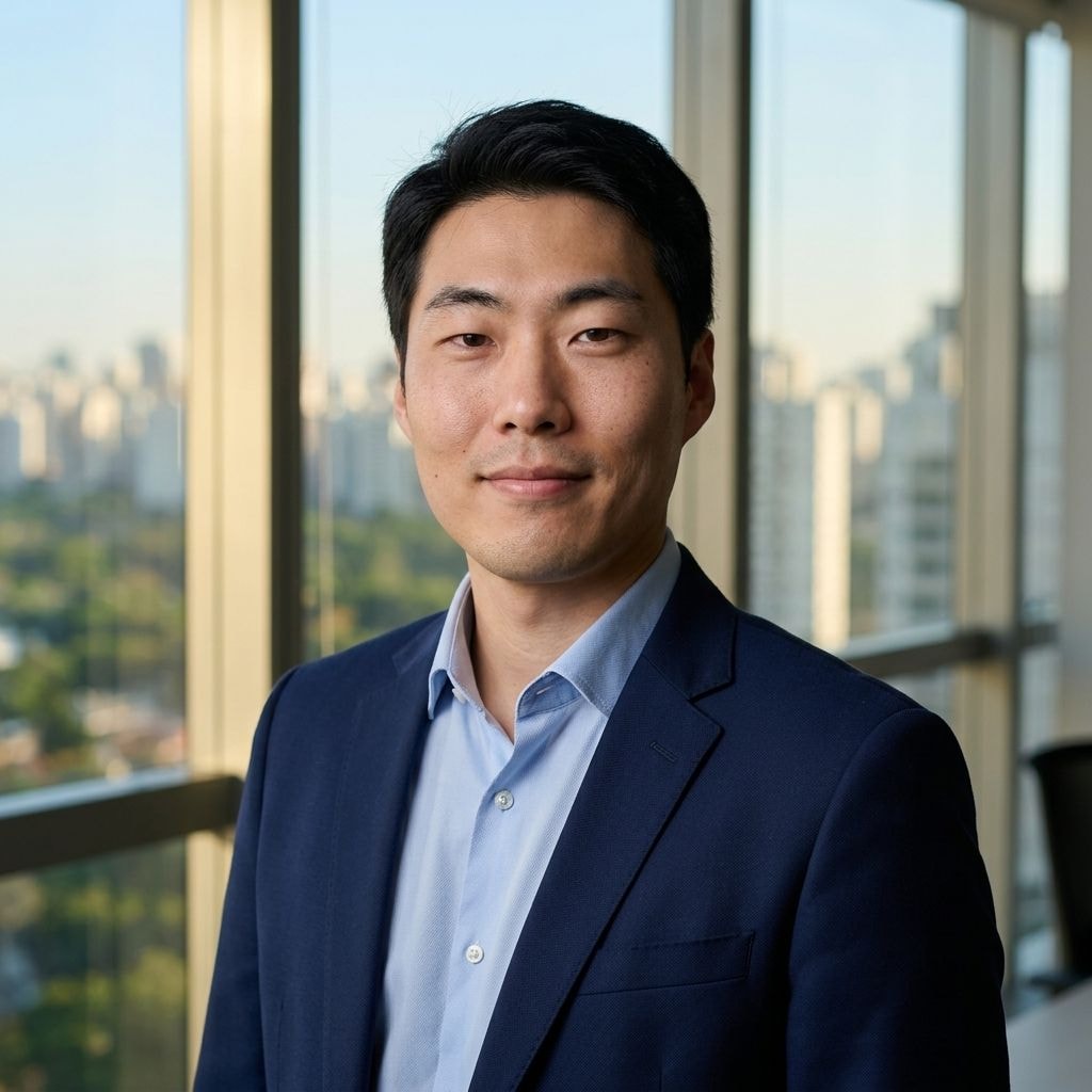 Saída real do Gemini Nano Banana 2 para o prompt 6.1 Corporativo Linkedin BR: mesmo homem da selfie de entrada, agora de blazer marinho sobre camisa azul-clara em escritório moderno de São Paulo com golden hour. Identidade preservada, mãos não visíveis.