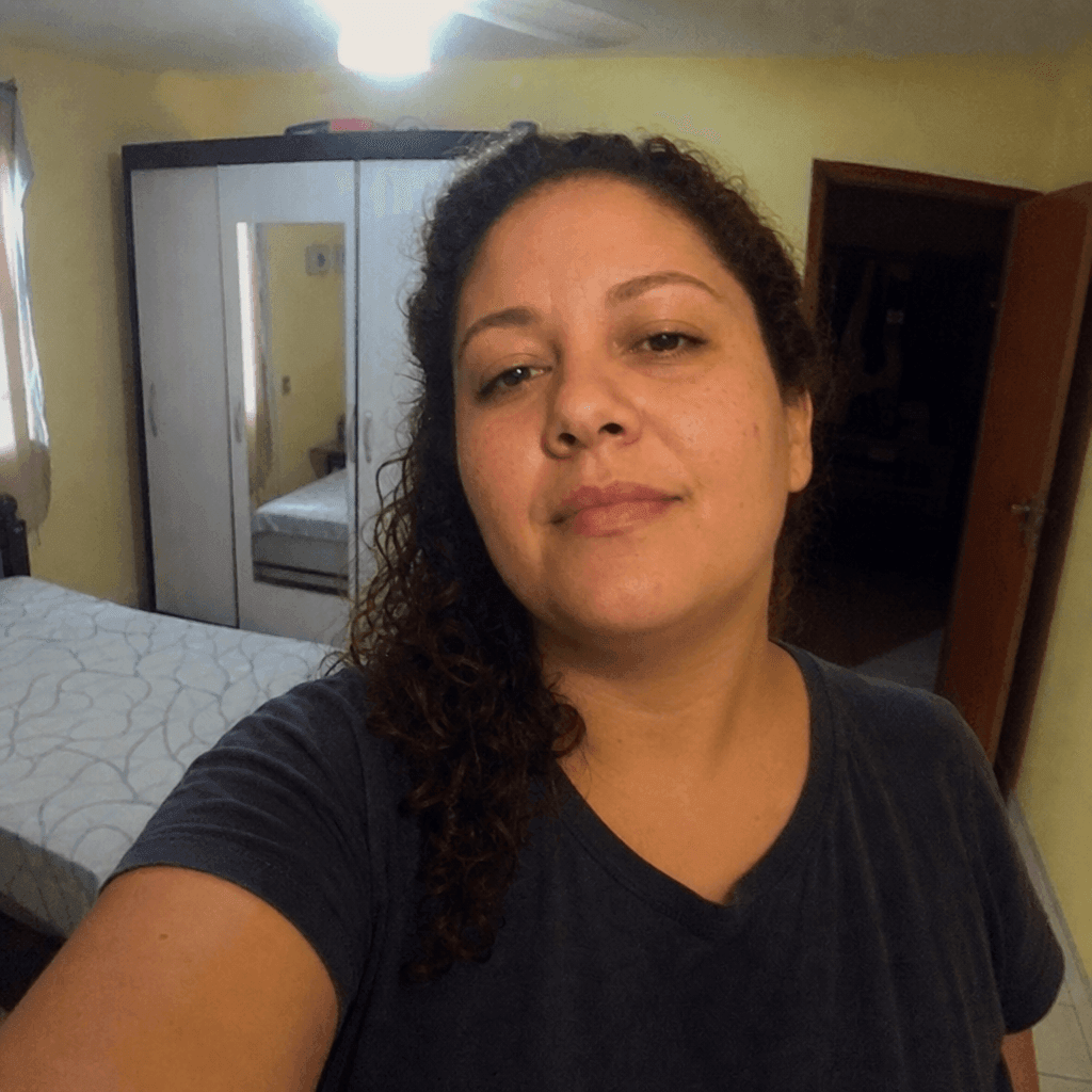 Selfie de entrada (mulher parda brasileira no começo dos 30 anos, plus-size, cabelo cacheado escuro, em casa) usada como input para o prompt 6.5 Foto pra currículo BR 3×4 no Gemini Nano Banana 2.